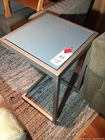 Side view of the metal frame side table positioned next to a couch and on a textured rug.