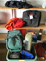 Overview of all items in the lot including suitcase, backpack, fan, and exercise accessories on wooden shelves