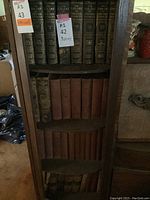 Full view of four shelves with antique books. The middle shelves contain brown covered volumes of 'Harper's Encyclopedia of United States History' and other unknown antique books.