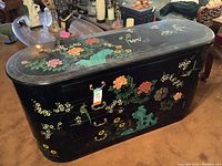 Front view of black enamel sideboard showing two drawers and double doors with floral and bird motifs