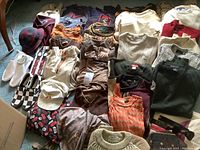 Overview of mens clothing lot with sweaters, hats, shoes.