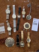 Overview of lot on brown carpet showing all eight watches and two pendants.