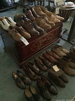 Full overview showing two rows of men's leather shoes including lace-ups, loafers, and boots in various shades of brown, tan, and black.