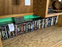 Wide shot showing a long row of DVDs lined up on a shelf beneath wooden cabinetry.