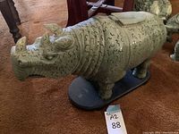 Full side view of the green jade rhinoceros sculpture on wooden base