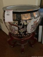 Front and side views of large ceramic planter showing detailed floral and nature paintings, and wooden support stand.