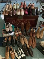 Six pairs of shoes and boots arranged on wooden chest; woven slip-ons, suede and leather shoes, velvet loafers.