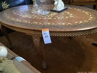 Full view of oval tabletop showing central floral inlay and carved edge