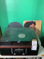 Full view of the TEAC turntable with a vinyl record on the platter and vinyl album covers visible behind it.