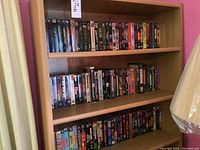Shelf with three rows full of a variety of VHS tapes including sci-fi and horror films.