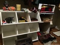 Wide photo of white cubby shelves and assorted items including linens, boxed scarf, decor, and fabric items
