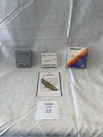 All four airline memorabilia items displayed on white cloth background: British Airways tin, Pan Am matchbox, Air Pacific matchbox, Boeing pin badge.