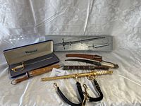 Photo showing all 7 items including swords, knives, and sheaths displayed on fabric background