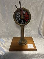 Front view of entire engine order telegraph mounted on wooden base showing dial.
