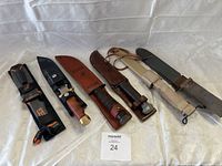 Overview of all six knives and sheaths laid out on cloth background