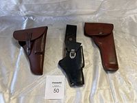Front view of three leather firearm holsters placed side by side on a white background.