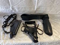 Set showing three black leather holsters with straps and one matching black leather gun belt with cartridge loops.
