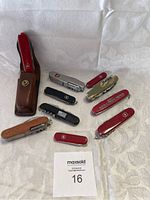 Overview of all 10 Swiss Army style knives and cutters including leather case and variety of handle colors and markings.