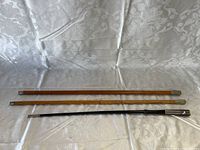 Three military swagger sticks laid side by side showing differing materials and metal accents.