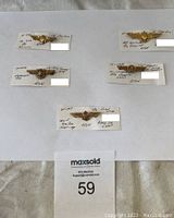 Five different USN pilot wings badges with handwritten notes on cards, placed on a white background.
