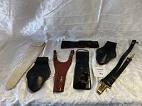 Full set of seven sword holsters and sheaths laid out on white fabric background.