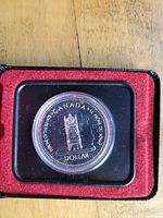 Photo of 1977 Canadian silver dollar coin "Throne of the Senate" in clear protective case with red velvet backing inside a black presentation box.