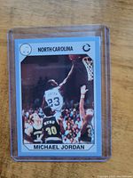 Front of the card showing Michael Jordan in North Carolina jersey number 23, jumping for a layup or dunk with opponents around, blue border, card number 89.