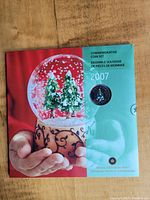 Cover of the 2007 commemorative coin set folder featuring a festive snow globe with evergreen trees; showing the 2007 year and Royal Canadian Mint branding.