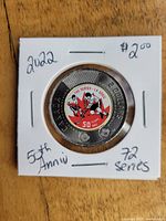 Close-up image of the 2022 Canadian $2 coin depicting the 50th anniversary commemorative design for the Canada vs Russia hockey series of 1972, mounted in a white cardboard coin flip holder with handwritten notes.