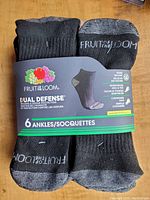 6 pairs of new black Fruit of the Loom ankle socks with packaging showing brand, features and size.