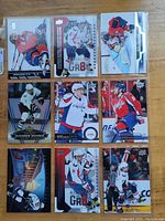 Photo of nine Alex Ovechkin hockey cards, various brands and series, in protective sleeves on wood surface.