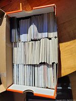 Box filled with numerous hockey trading cards arranged in rows, showing the quantity and storage method.