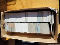 Photo of a box filled with a large number of hockey trading cards loosely stacked in rows.