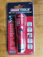 Front view of OEM Tools Mini 1 Watt LED rechargeable flashlight in sealed retail packaging showing product and specifications.