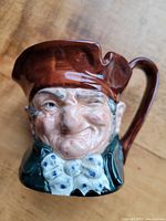 Front and side photo showing the detailed facial features, hat, and bow tie on the Royal Doulton Toby mug 'Old Charley'.