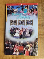 Full view of the themed packaging for the Festival of the Fathers coin, featuring photos of people in traditional Canadian attire and festival scenes.