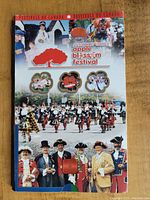 Photo of the colorful souvenir folder covering the Annapolis Valley Apple Blossom Festival with images of festival participants and traditional costumes.