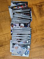 Photo of a mixed lot of Upper Deck hockey cards spread on a wooden surface showing various players in action poses.