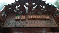 Full front view of bench with carved bear backrest and seat with decorative wooden letter blocks
