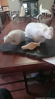 Three white marble polar bear sculptures mounted on dark stone base displayed on wood table.