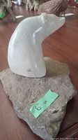 Oblique side view of smooth white marble animal head sculpture on natural rock base with size notation '6''