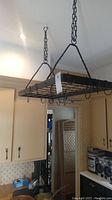 Full view of the black metal hanging rack installed in kitchen ceiling, showing the rectangular grid frame and hooks.