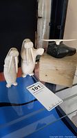 Photo showing two carved walrus sculptures and a carved owl on stone base placed on a wooden block