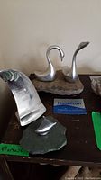 Metal sculptures on display with stone bases, highlighting two swan figures and other abstract forms.