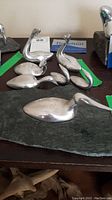 Set of seven aluminum bird sculptures on a table with green tape and Hoselton card visible