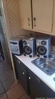 Sony stereo system with two speakers positioned on kitchen counter beside sink.