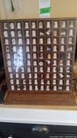 Front view of full wooden display case containing 72 collectible thimbles.