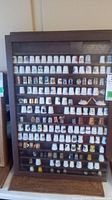 Full view of wooden framed display case filled with multiple rows of decorative thimbles.