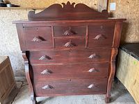 Front view of antique wood dresser showing decorative handles and scalloped top panel.