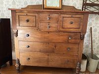 Front view of antique wooden dresser with three smaller top drawers and three larger bottom drawers, each with round wooden knobs and keyholes